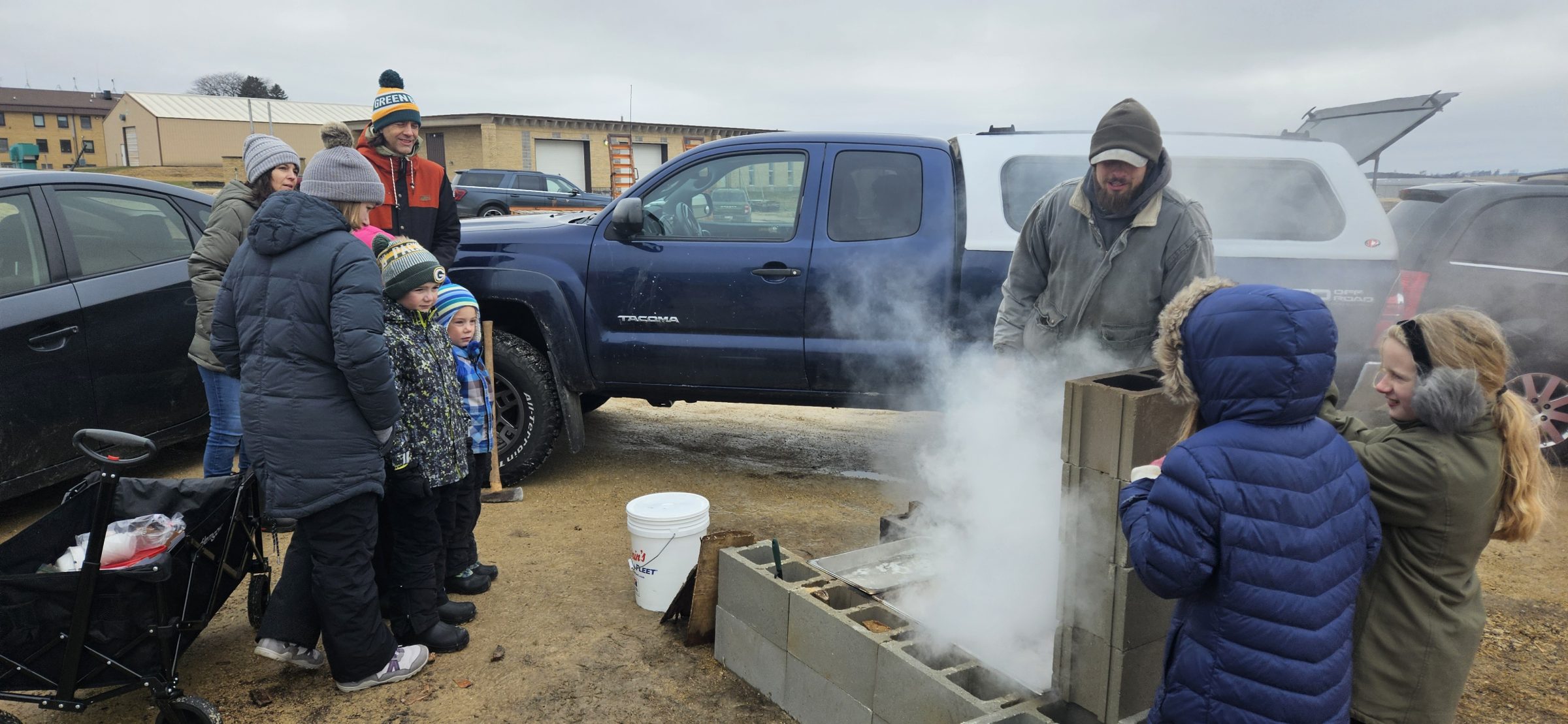 People gathered around the fire to cook maple sap until it turns to syrup.